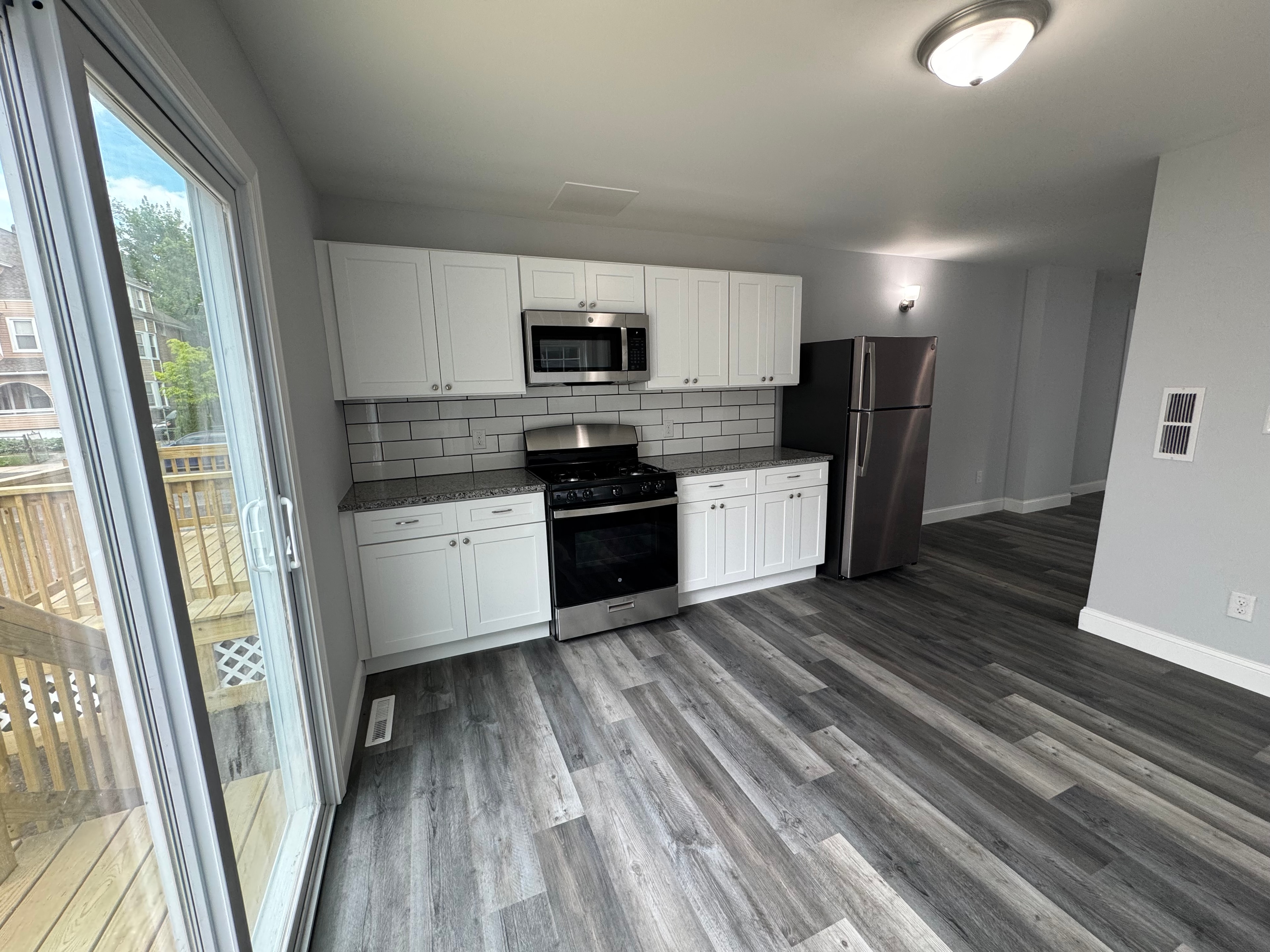 Completed kitchen renovation with white cabinetry, subway tile backsplash, and new hardwood flooring